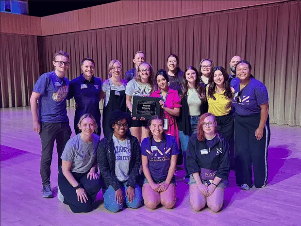 Nazareth University staff at the annual conference holding a commemoration plaque.